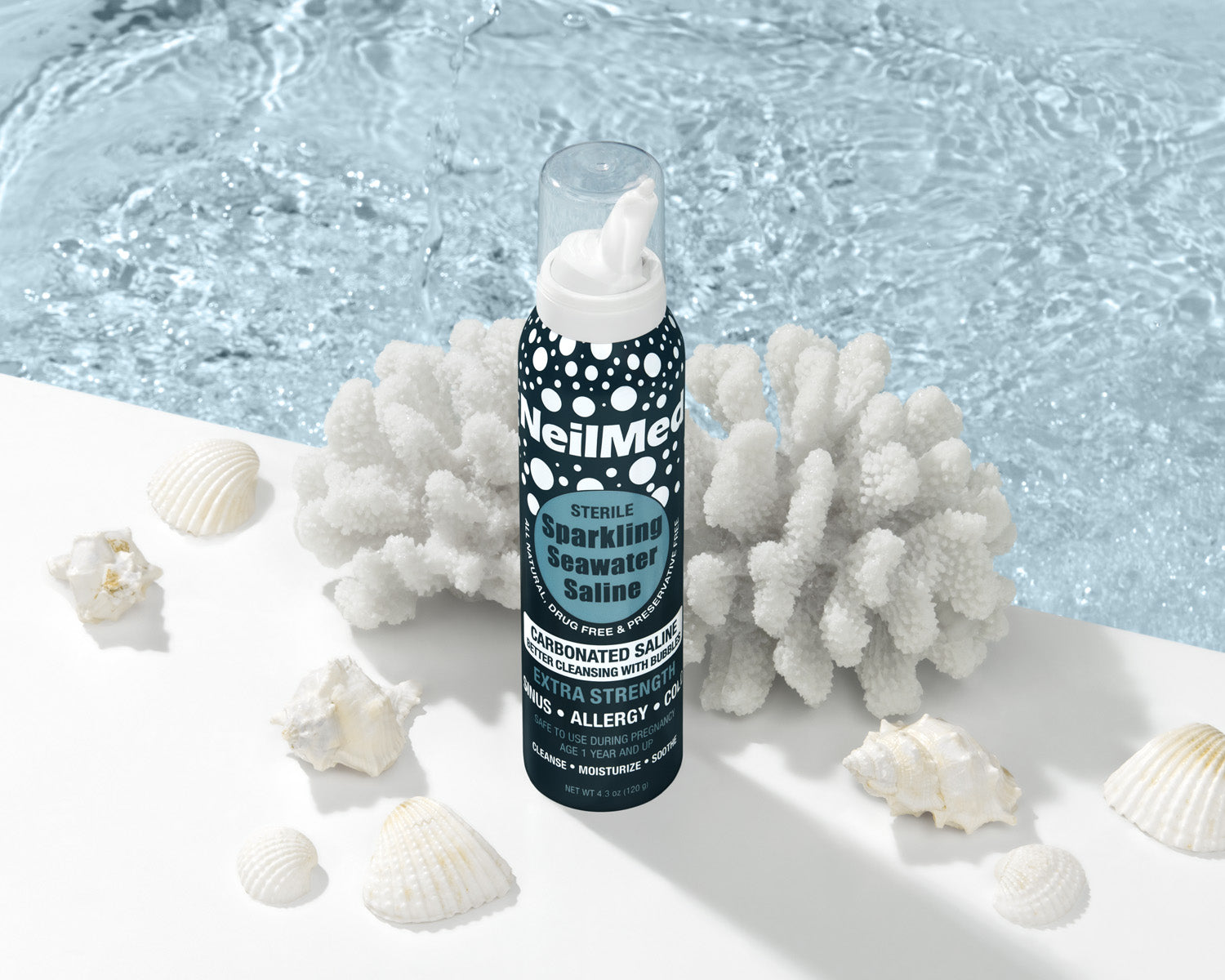 Bottle of WellMed Sterile Sparkling Seawater Saline with coral and shells on a light background
