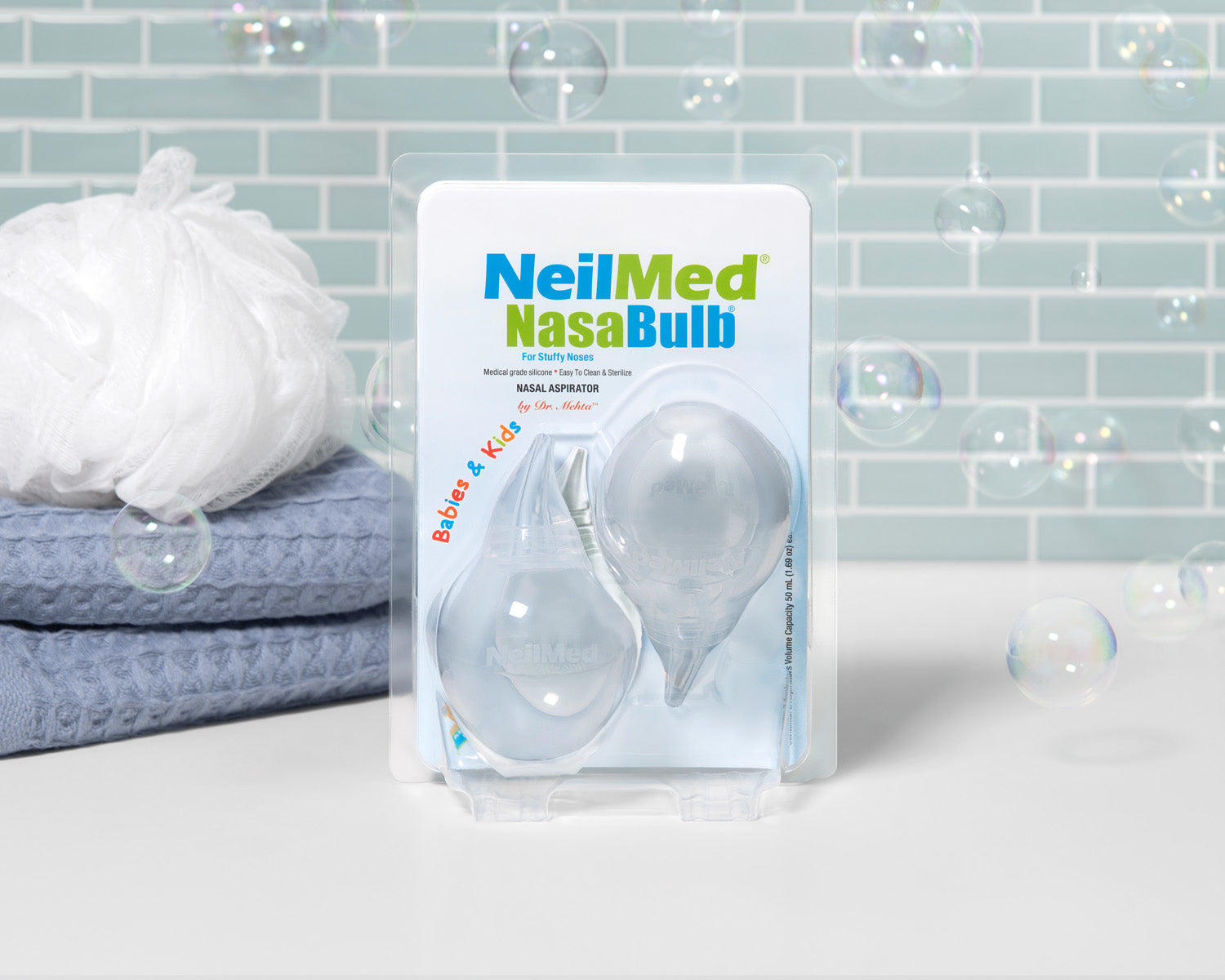 NeilMed NasaBulb packaging with a blue towel and white pillow in the background