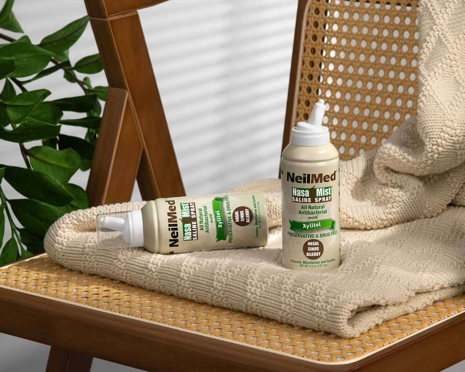 Two bottles of NeilMed products on a woven chair with a plant in the background